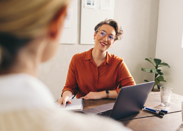 Happy hiring manager smiling while interviewing a job candidate in her office. Cheerful businesswoman having a meeting with a shortlisted job applicant in a creative workplace.