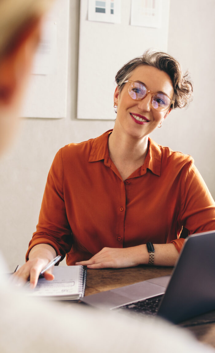 Happy hiring manager smiling while interviewing a job candidate in her office. Cheerful businesswoman having a meeting with a shortlisted job applicant in a creative workplace.