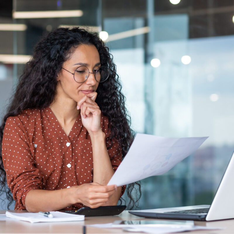 Successful satisfied and happy business woman working inside modern office, hispanic woman in glasses and shirt using laptop at work,